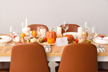 Festive table setting for Thanksgiving Day with pumpkins, greeting cards and candles