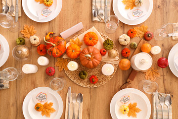 Festive table setting for Thanksgiving Day with pumpkins, greeting cards and candles