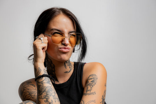 Playful portrait of a tattooed girl making a puckered lip facial expression