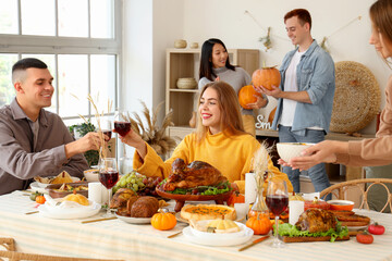 Group of young friends having dinner at festive table on Thanksgiving Day
