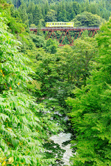 比立内川に架かる比立内橋梁を渡る緑色の秋田内陸線の気動車