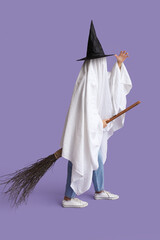 Woman in Halloween costume of ghost and witch hat with broom on lilac background