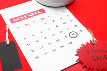 Calendar with date 24 NOVEMBER and discount tag on red background, closeup. Black Friday sale