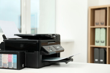 Modern printer with paper on white table in office