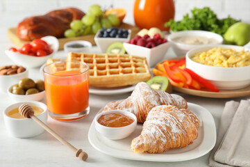 Tasty breakfast. Croissants, jam, honey and other food on light table