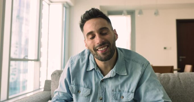 Cheerful handsome Latin freelance business man saying hello, goodbye at camera, waving greeting hand, smiling, speaking on video conference call, broadcasting online. Male head shot portrait