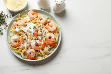Delicious pasta with shrimps and creamy sauce on white marble table, flat lay. Space for text