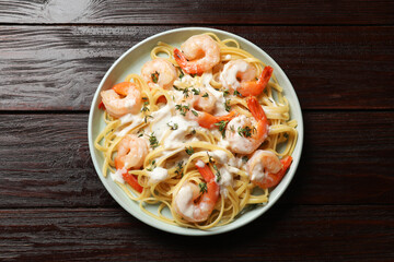 Delicious pasta with shrimps and creamy sauce on wooden table, top view