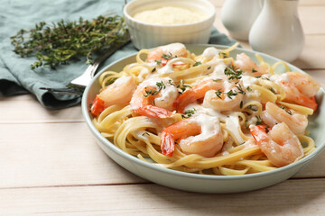 Delicious pasta with shrimps and creamy sauce on light wooden table, closeup