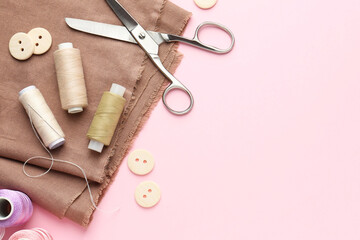 Flat lay composition with different sewing supplies on pink background. Space for text