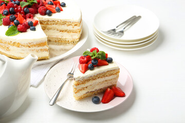 Tasty sponge cake with fresh berries and mint served on white table