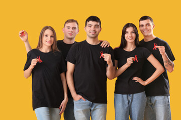 Group of young people with red ribbons on yellow background. World AIDS day concept