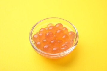 Bright tapioca pearls in bowl on yellow background, closeup