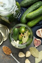 Making pickles. Fresh cucumbers and spices in jars on grey table, flat lay