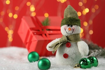 Cute decorative snowman and other Christmas decor on artificial snow, closeup