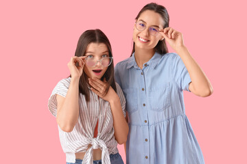 Young women in eyeglasses on pink background