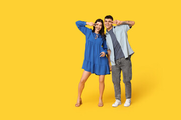 Happy young couple dancing on yellow background