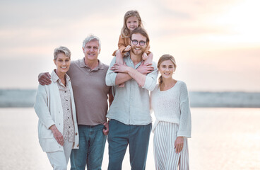 Portrait of senior, parents and child on beach for bonding, relaxing and travel together in nature. Family generation, happy and mom, dad and girl by ocean for holiday, vacation and adventure by sea