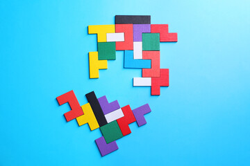 Colorful wooden puzzle pieces on light blue background, top view