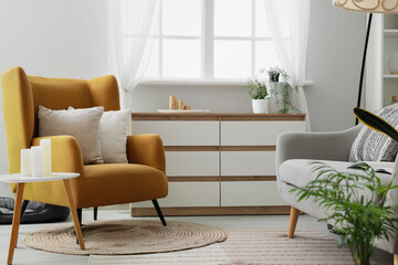 Armchair with cushions near coffee table with candles in living room