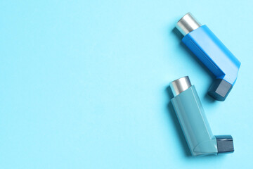 Asthma inhalers on light blue background, flat lay. Space for text