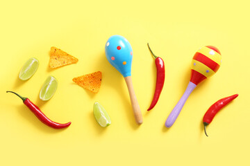 Composition with Mexican maracas, chili peppers, nachos and lime on yellow background. El Dia de Muertos