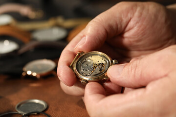 Man with mechanism of vintage wrist watch at table, closeup