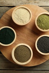 Different superfood powders in bowls on wooden table, top view