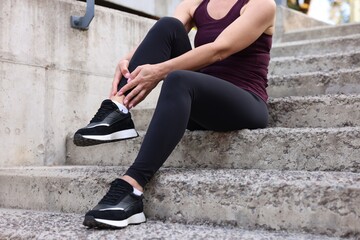 Woman suffering from foot pain on steps, closeup