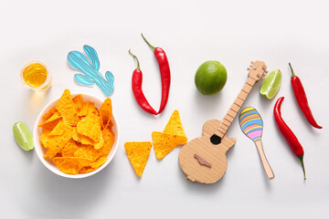 Composition with tasty nachos, tequila, chili peppers and decor on light background. El Dia de Muertos