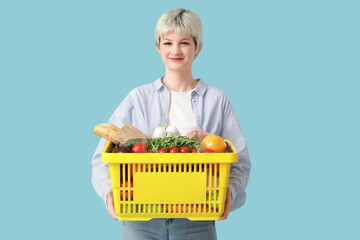 Young woman with full shopping basket on blue background