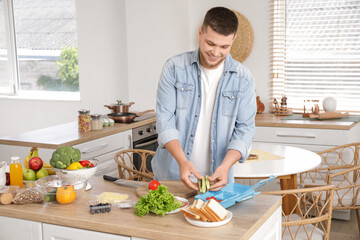 Young man cutting vegetables for lunch box in kitchen