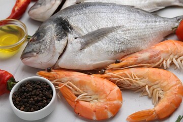 Fresh raw sea food and products on white tiled table, closeup