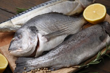 Sea food. Different types of raw fish, rosemary and lemon on wooden table, closeup