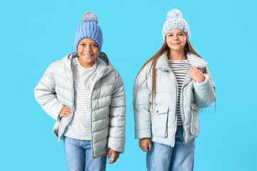 Cute little happy children in winter clothes on blue background