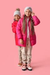 Cute little happy children in winter clothes on pink background