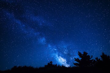 Naklejka premium A stunning natural spectacle, often seen in remote areas with minimal light pollution, where countless stars create a breathtaking celestial display against the deep blue night sky, ai