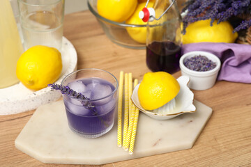 Glass of fresh lavender lemonade and juicer with lemon on wooden table