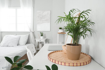 Fototapeta premium Laptop with decor on table near comfortable bed at home, closeup
