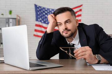 Handsome young tired businessman with flag of USA in office