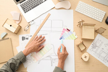 Male furniture designer with color palettes working on table, top view