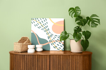 Modern interior of living room with tropical monstera leaves in pot on chest of drawers, closeup © Pixel-Shot