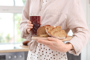 Young woman with glass of tasty kvass and bread slices in kitchen, closeup