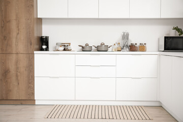 Interior of light kitchen with white counters and utensils