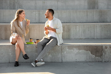 Young colleagues with coffee having lunch outdoors