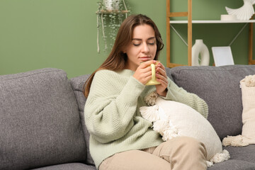 Beautiful woman drinking tea on sofa at home