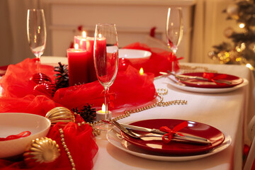 Christmas table setting with burning candles in dark room, closeup