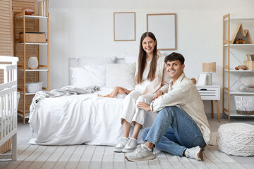 Happy young parents with their little baby in bedroom