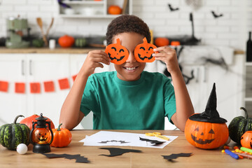 Teenage African-American boy with paper Halloween pumpkins at home