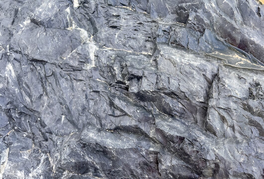 Extremely close up of an interesting hard rock on dark grey shiny  texture pattern of featuring surface pattern highlights background.	